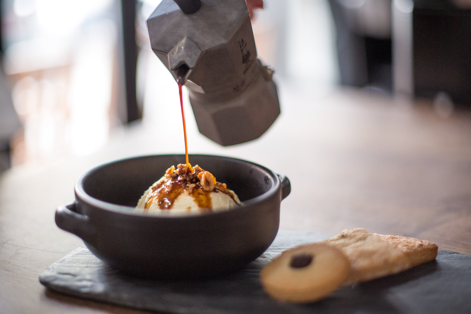 A gelato dessert being photographed as coffee is being poured on top.