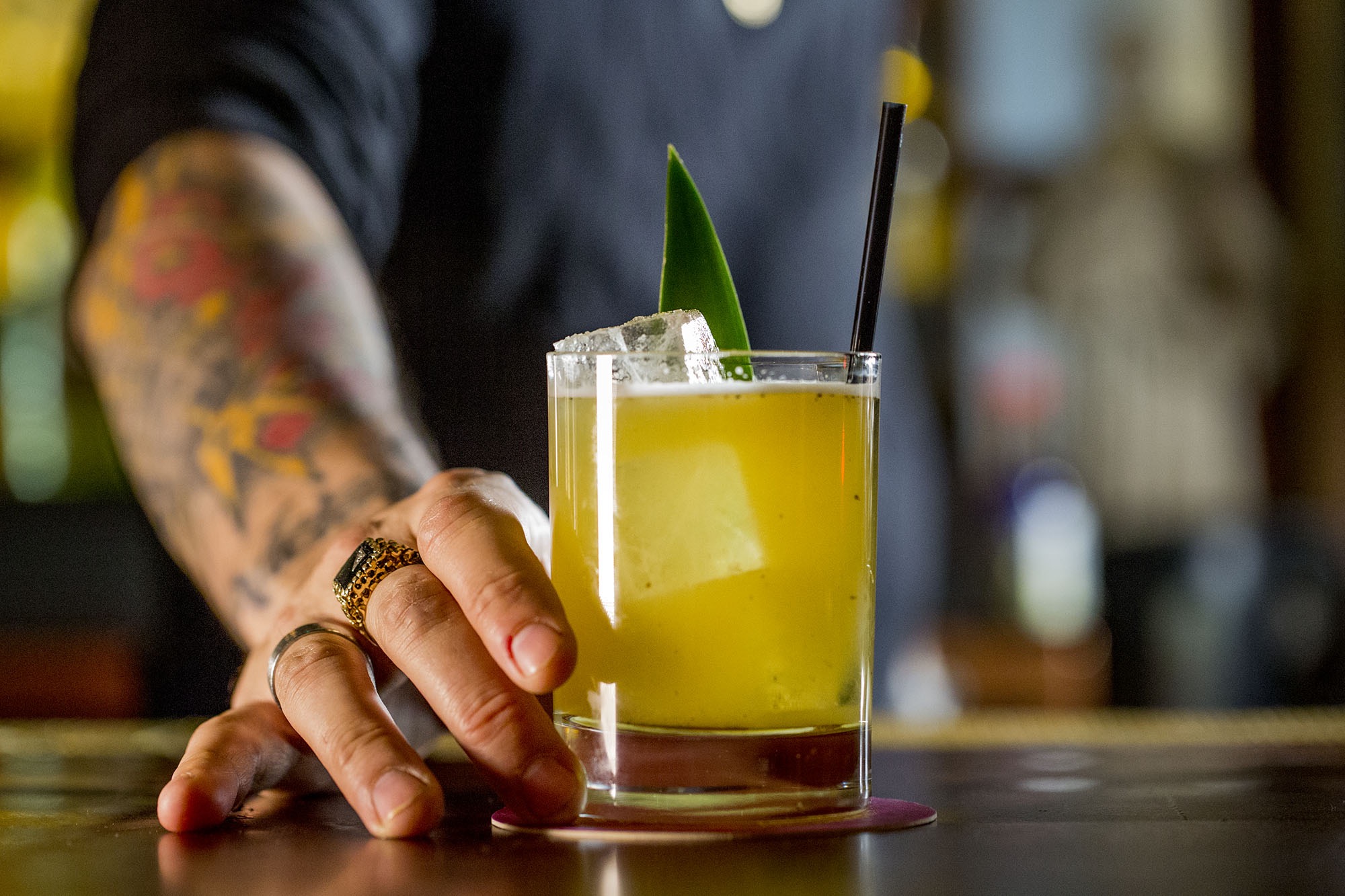 A tatooed bartender serving a drink.
